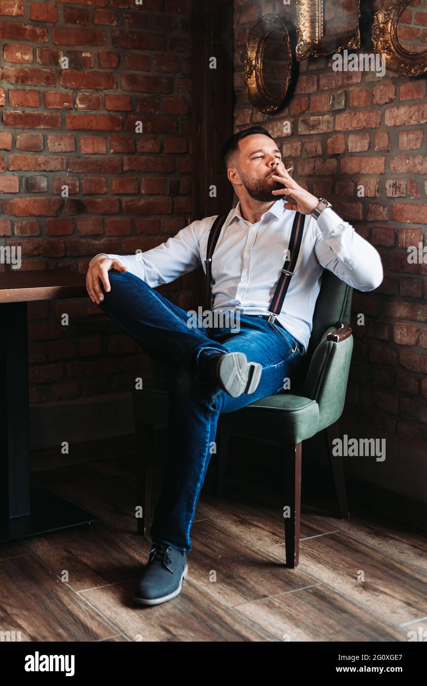 Handsome young man enjoying a cigarette inside of a cafe Stock Photo