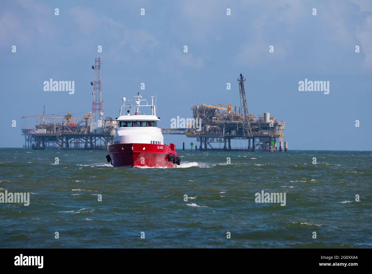 The Dauphin Island ferry heads toward the dock with an oil drilling rig