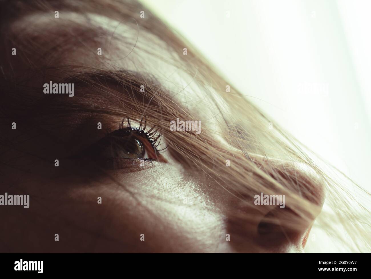 messy hair in the face of a woman with back light and bright eyes Stock Photo