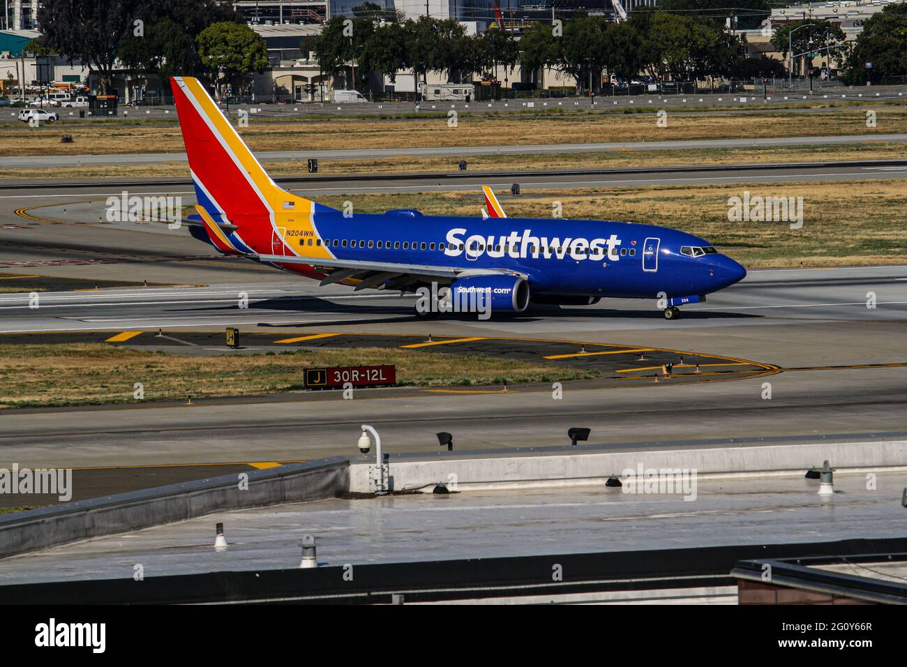 A Southwest 737 turns right off 30R and taxis to the gate. Stock Photo