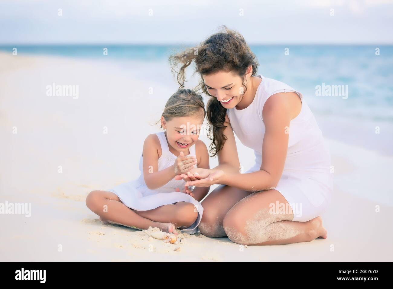 Mother with little daughter playing on ocean beach, Maldives. Family on the beach concept. Stock Photo