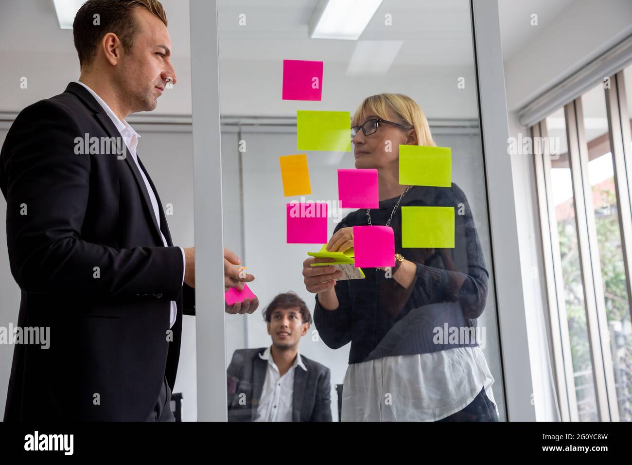 Businessman and Businesswoman tracking tasks on board. Using task control of agile development methodology in the office Stock Photo