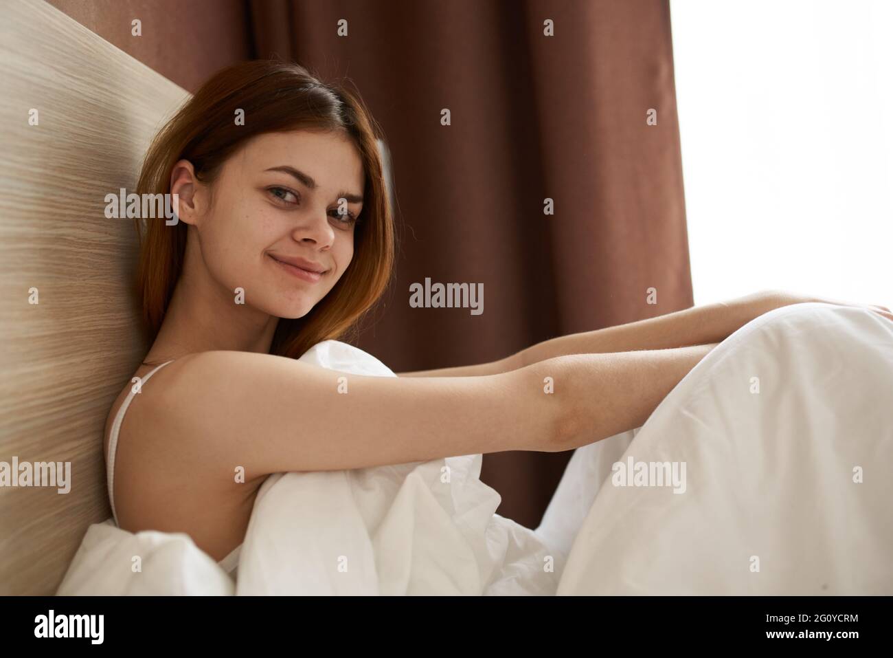 Happy Woman Under The Covers In Bed Near The Window In The Morning happy-woman-under-the-covers-in-bed-near-the-window-in-the-morning