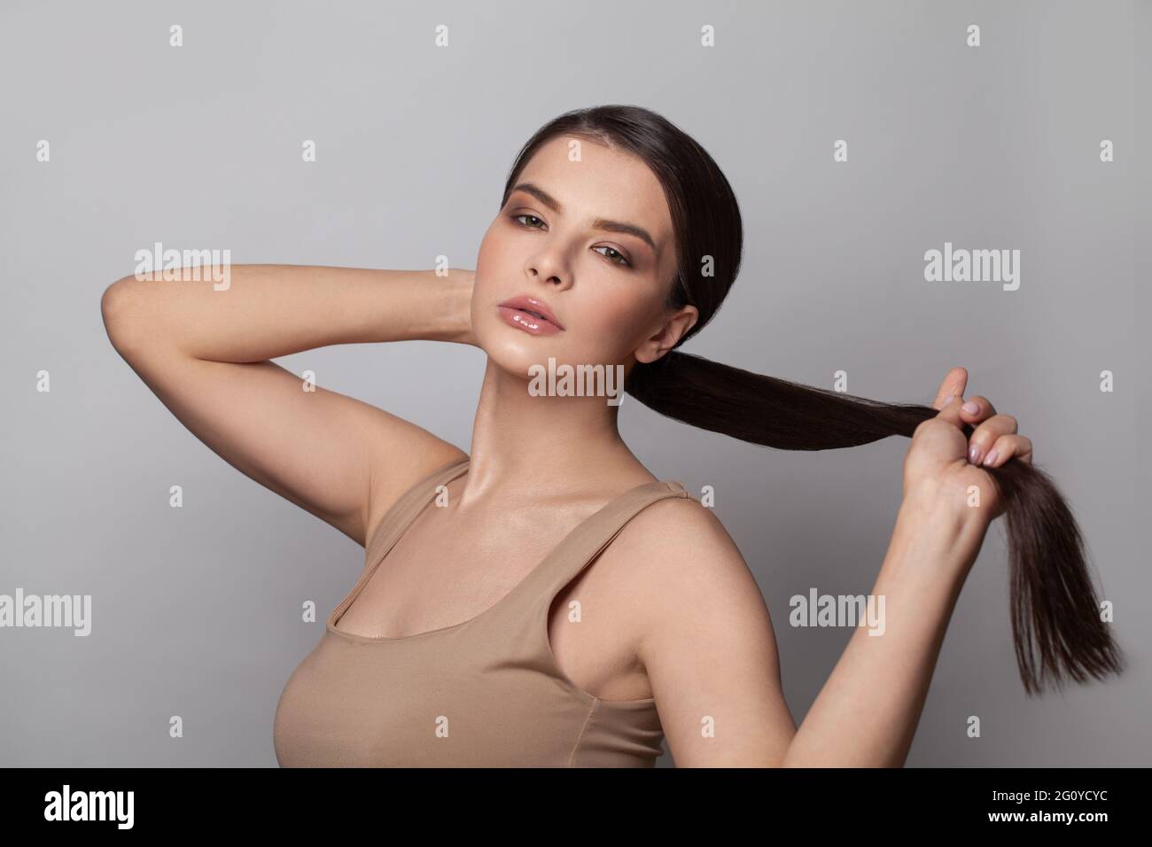 Beautiful young woman touching her ponytail hairstyle with smooth straight  hair Stock Photo - Alamy