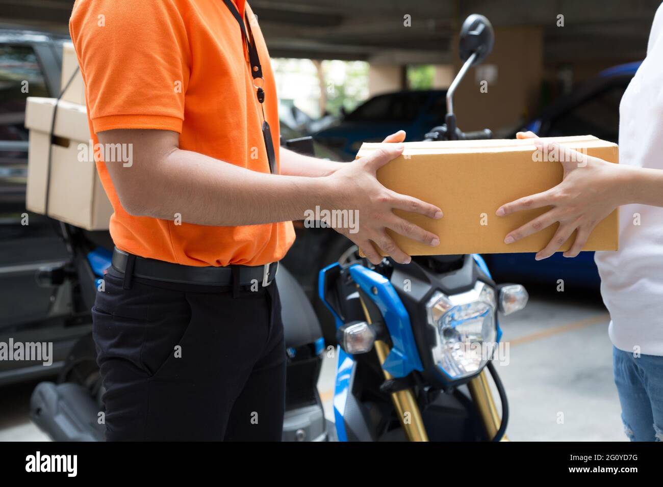 Woman hand accepting a delivery of boxes from deliveryman, Deliver goods by motorcycle service, Fast and Free Transport Stock Photo