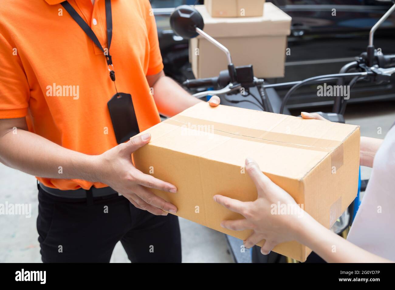 Woman hand accepting a delivery of boxes from deliveryman, Deliver goods by motorcycle service, Fast and Free Transport Stock Photo