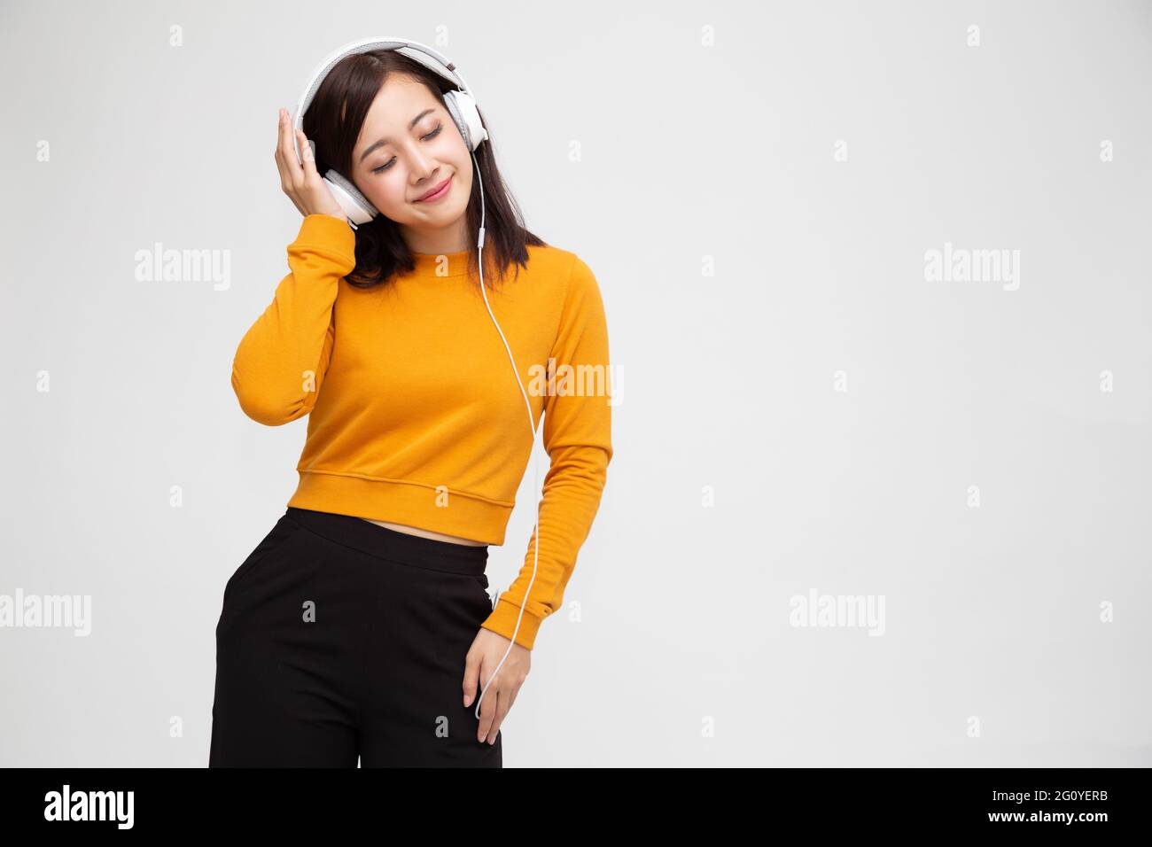 Beautiful young Asian woman with headphones listening to music in ...