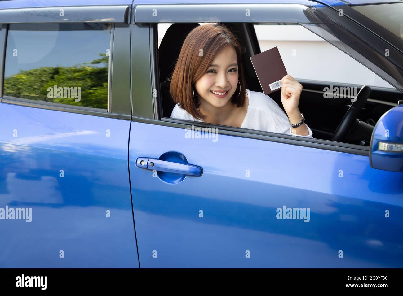 Happy Asian woman holding passport book and sitting in car, Rent a car of foreign for tourist traveler concept Stock Photo