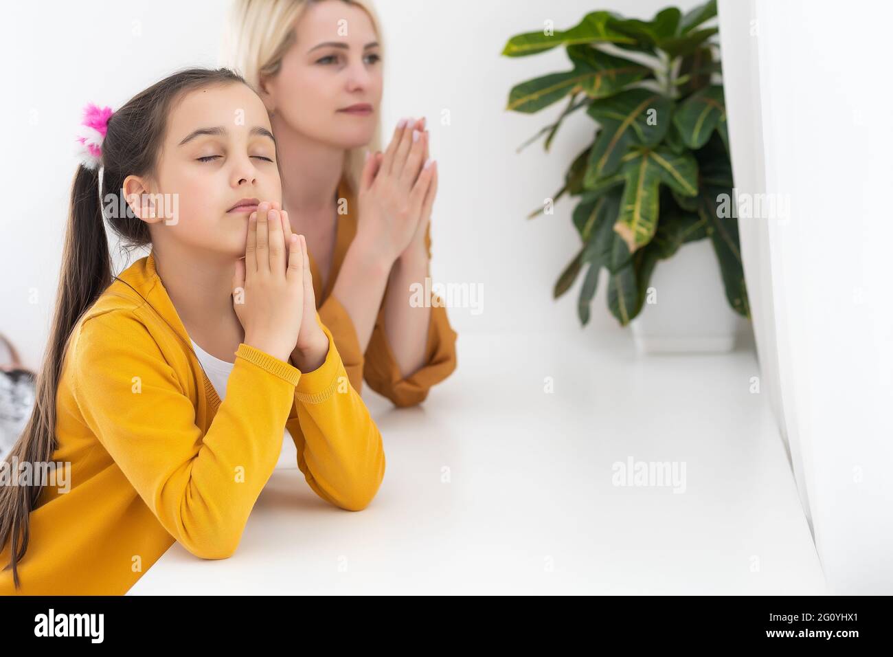 Mother and daughter reading from the bible and praying Stock Photo