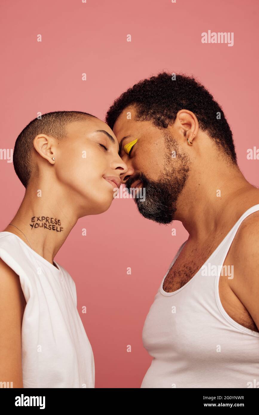 Man wearing makeup and bald woman with express yourself written on her neck. Stock Photo