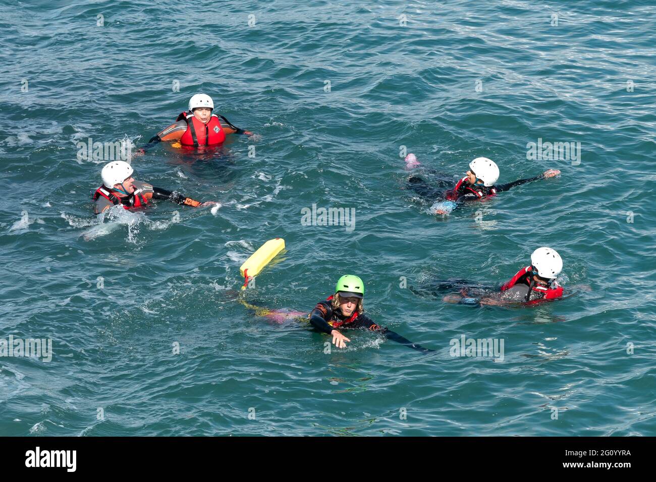 Holidaymakers and their guide swimming in the sea on a coasteering adventure on Towan Head in Newquay in Cornwall. Stock Photo