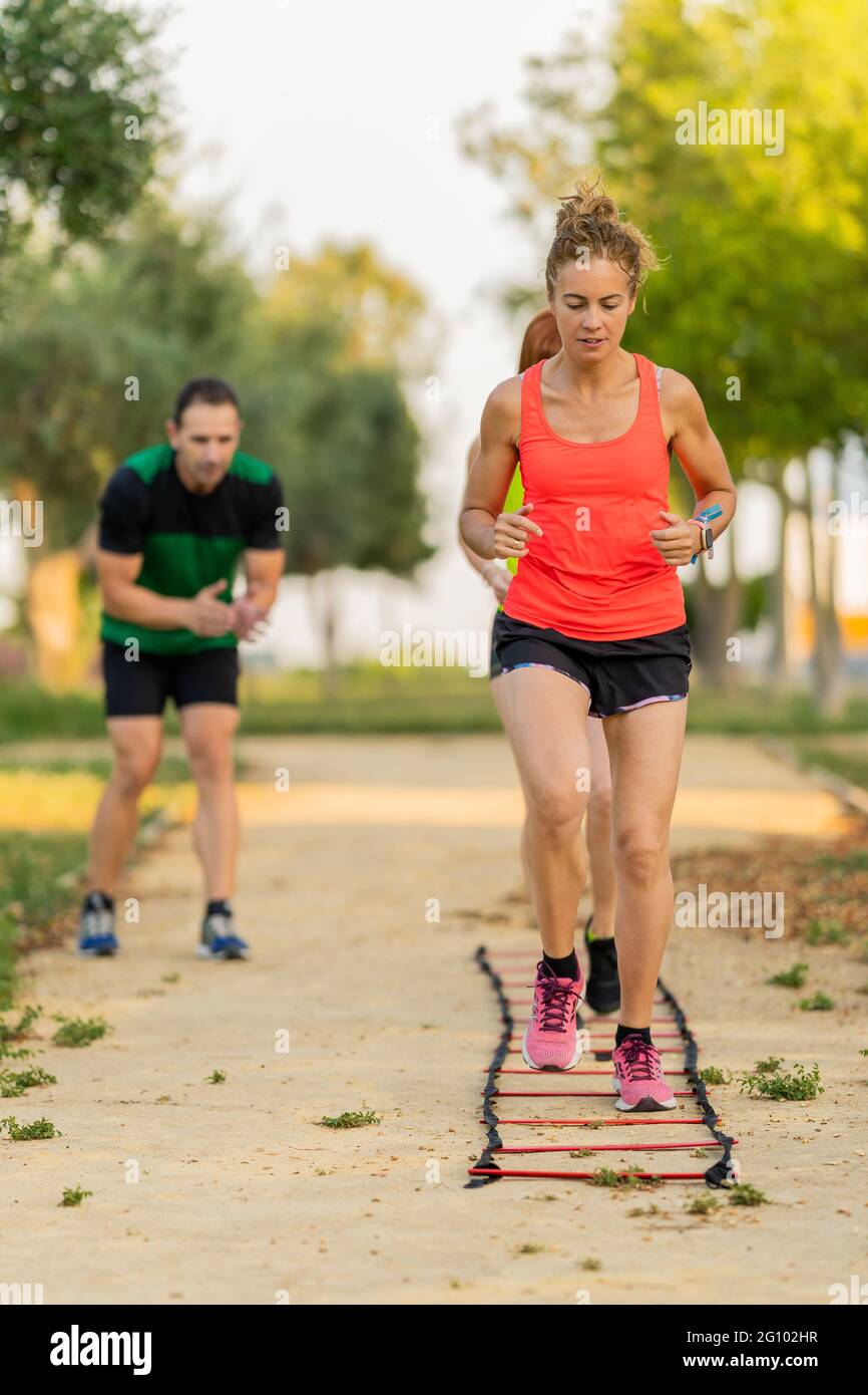 Strong women doing fitness circuit in the park and working out with their personal trainer. Stock Photo