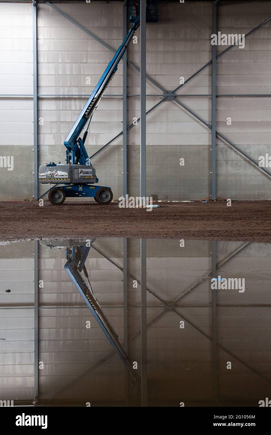 VENLO, NETHERLANDS - Feb 01, 2018: An aerial platform in a warehouse under construction. The aerial platform is reflected in the water. Stock Photo