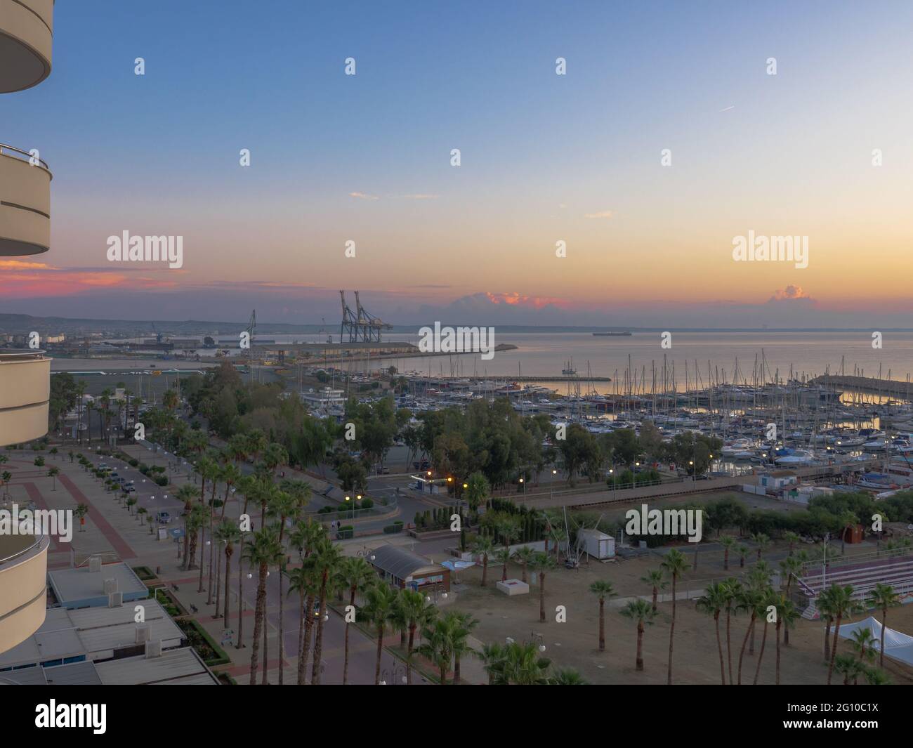 Top aerial view overlooking the sunrise at Finikoudes Palm tree promenade and pier with yachts near the Mediterranean sea in Larnaca city, Cyprus. Stock Photo