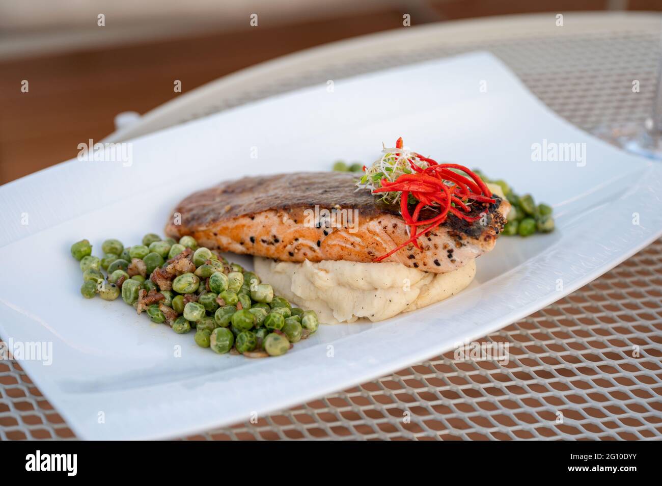 Close up of Grilled salmon with green peas, mashed potato in white plate on dining table Stock Photo