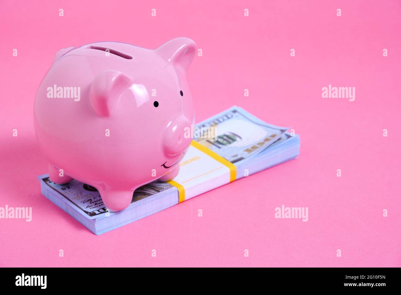 Pink Piggy Bank and a Stack of Hundred Dollar Bills on a Pink ...