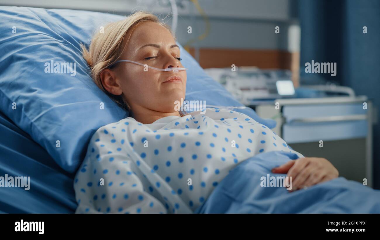 Hospital Ward: Portrait of Beautiful Young Woman Sleeping in Bed, Fully Recovering after Sickness. Female Patient Dreaming About Her Happy Healthy Stock Photo
