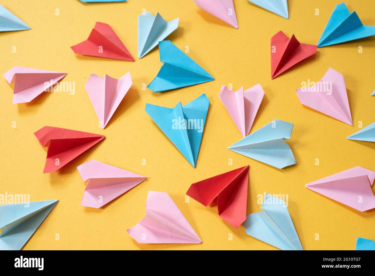 colorful origami paper airplanes on yellow colored background