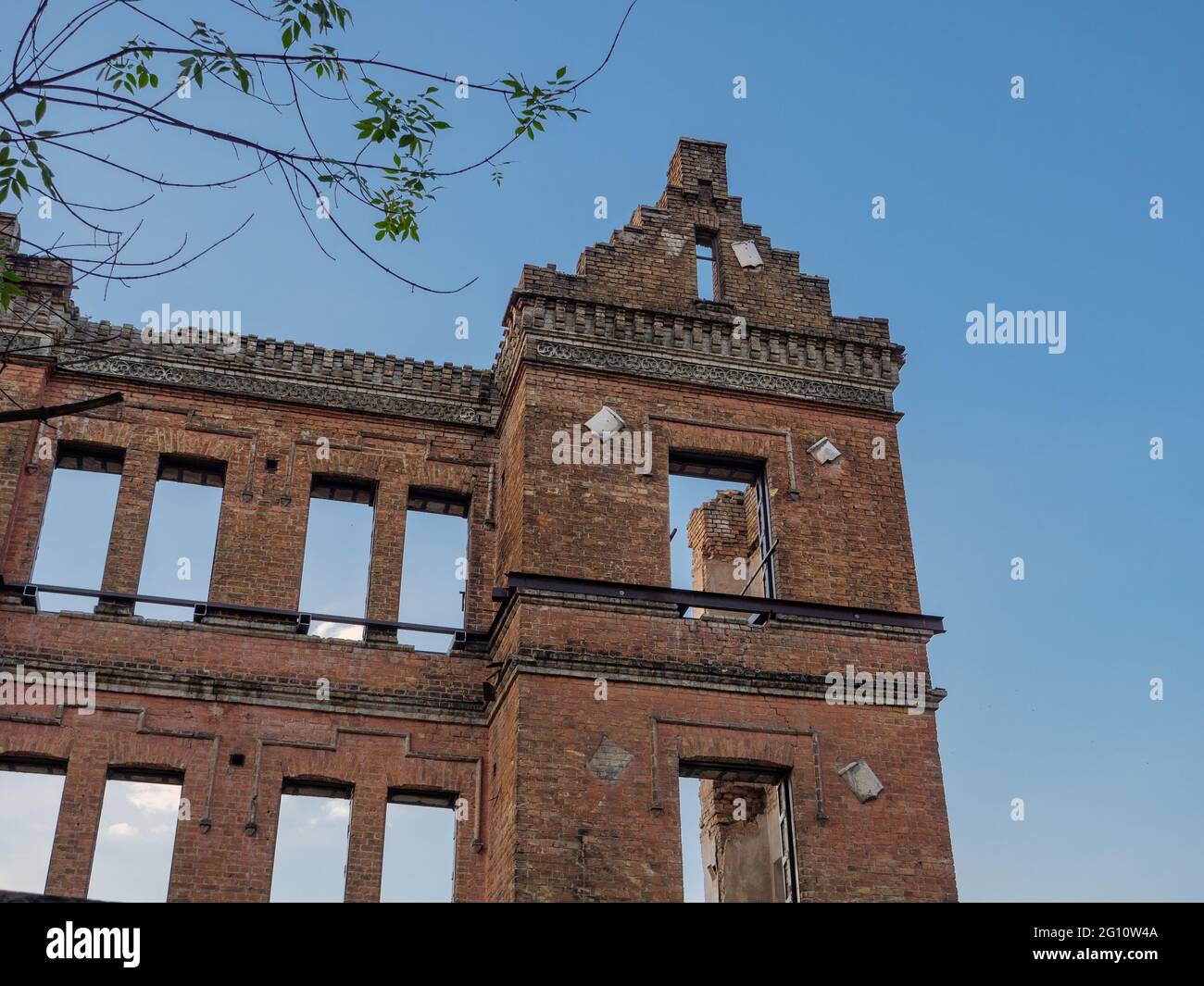 Exterior red-brick walls of an ancient half-ruined building with beautiful plaster work molding. Reconstruction concept. Stock Photo