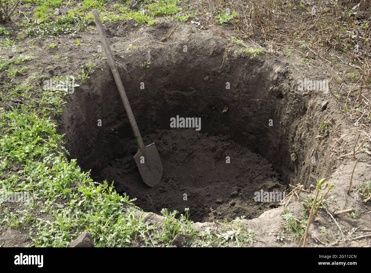 Deep pit in the ground. In the pit lies a shovel. Digging a hole. Stock Photo