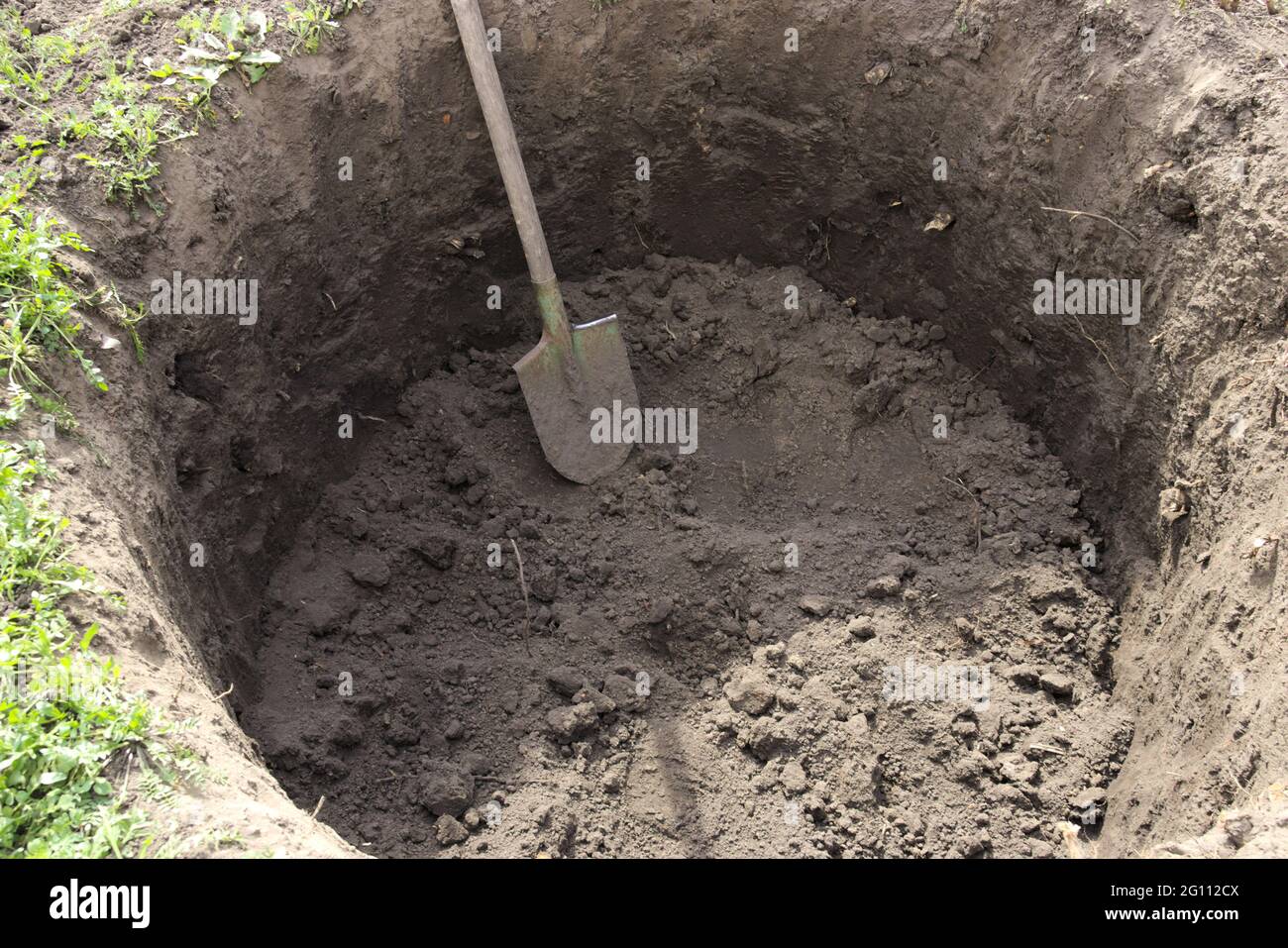 Deep pit in the ground. In the pit lies a shovel. Digging a hole. Stock Photo