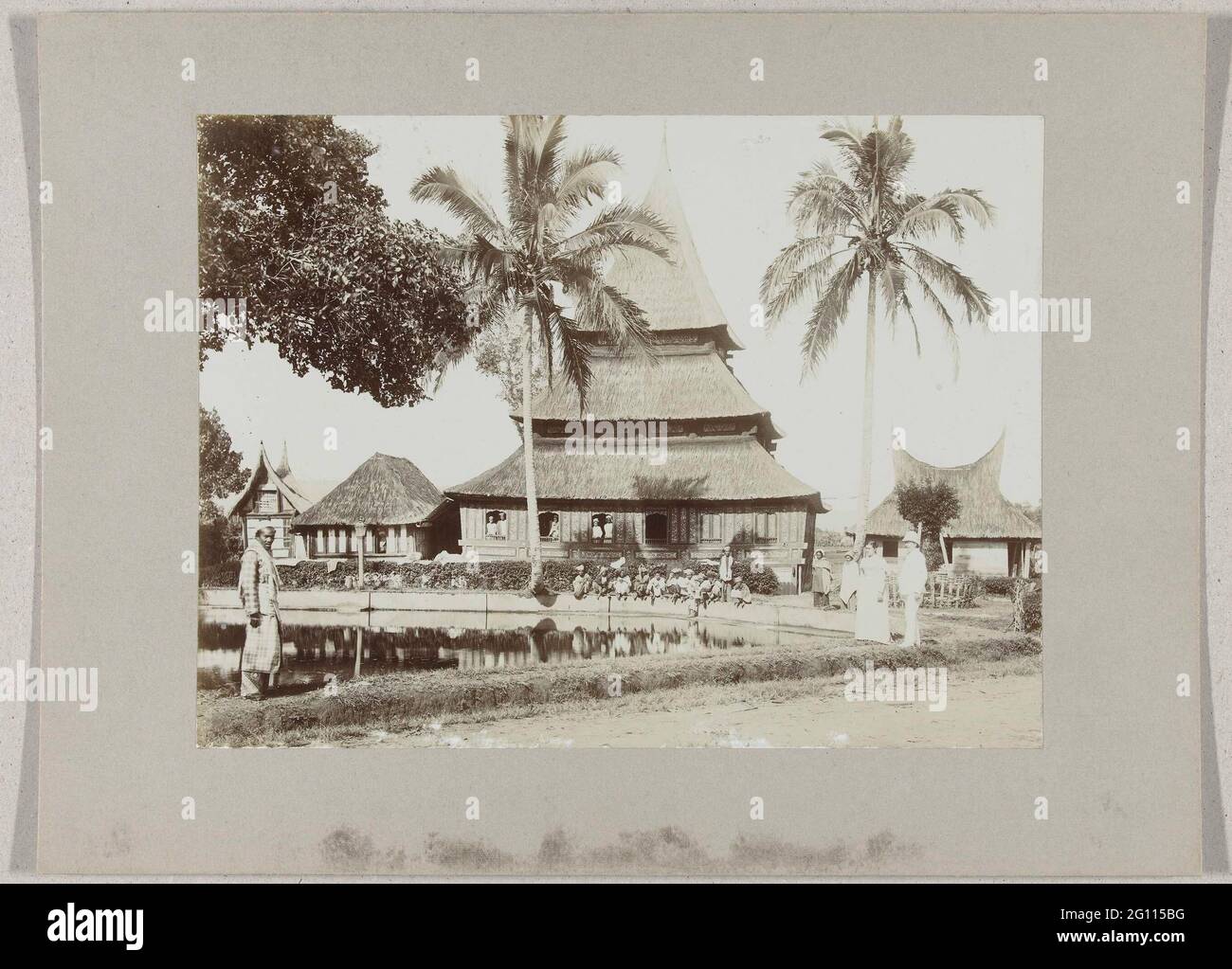 Mosque with fish pond in Kampong Talank at Fort de Kock; 6. Visch pond Fort De Kock. Mosque with fish pond in Kampong Taluk at Fort de Kock, Sumatra, Dutch East Indies. On the right a western couple, children at the edge of the pond. Stock Photo