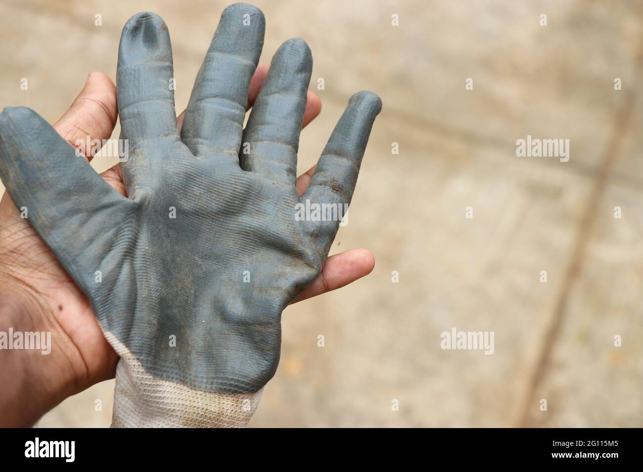 Working gloves held in hand after garden works with clean hands underneath. Protective gloves to safeguard hands on work process Stock Photo