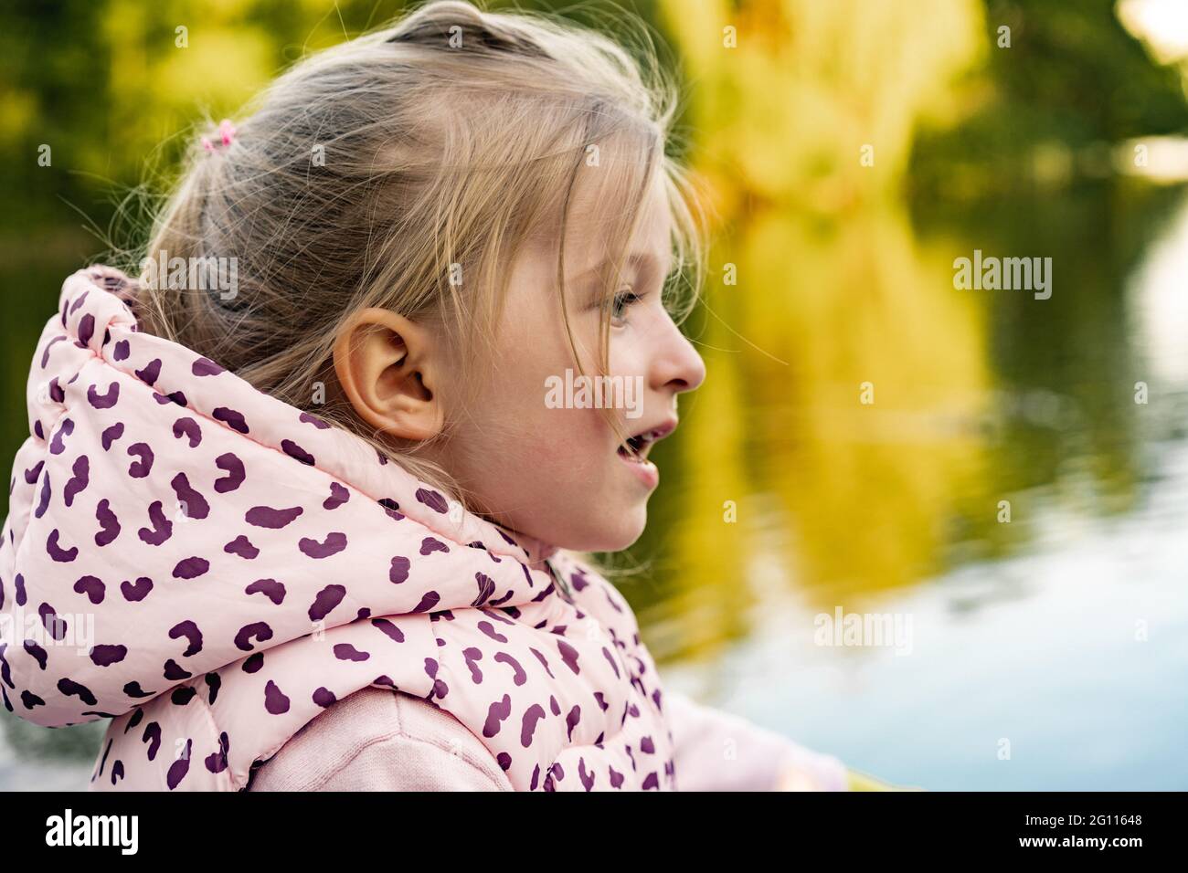Little girl sitting in park near the lake Stock Photo - Alamy