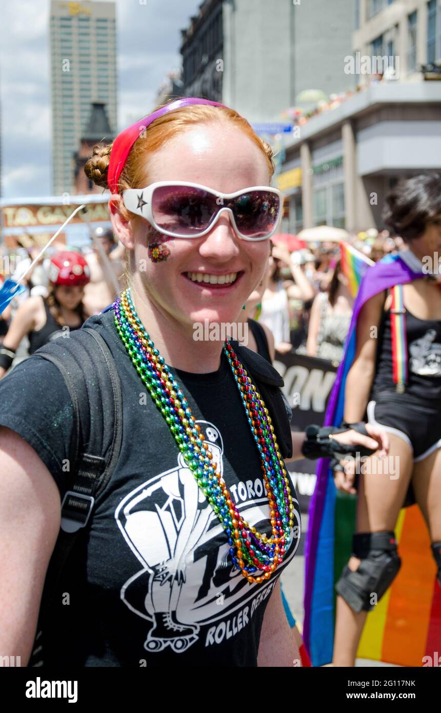 Smiling woman at pride parade in Toronto, medium shot of a reveler with painted face with out of focus crowd  in the background Stock Photo
