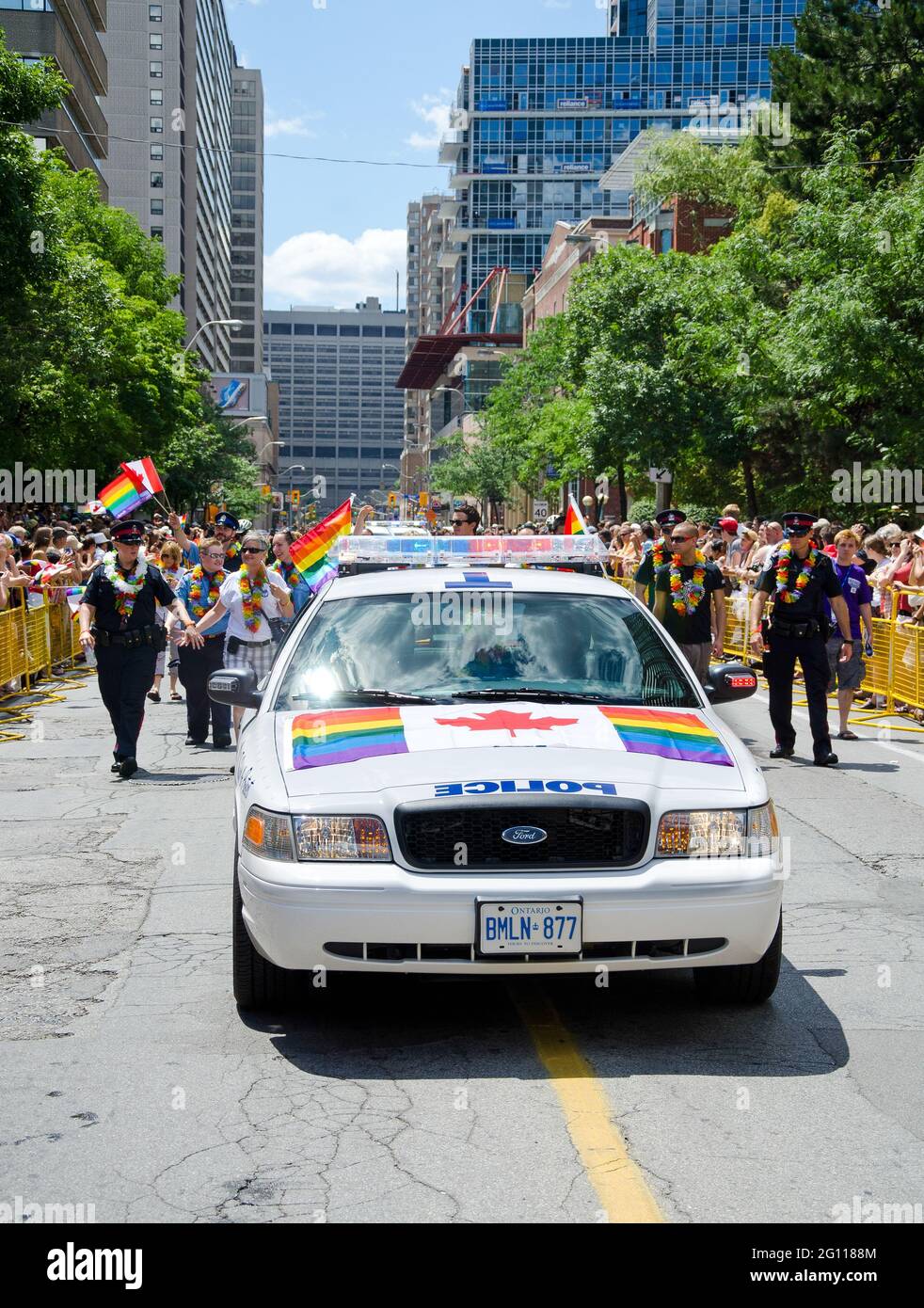 Toronto Pride Parade scenes: A police car decorated with gay pride flags oversees a pride parade while demonstraters follow behind in the street. Stock Photo