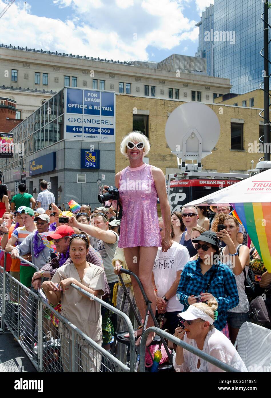 Toronto Pride Parade scenes: Photographer dressed in a pink dress and blonde wig while demonstrating at a pride parade. Stock Photo