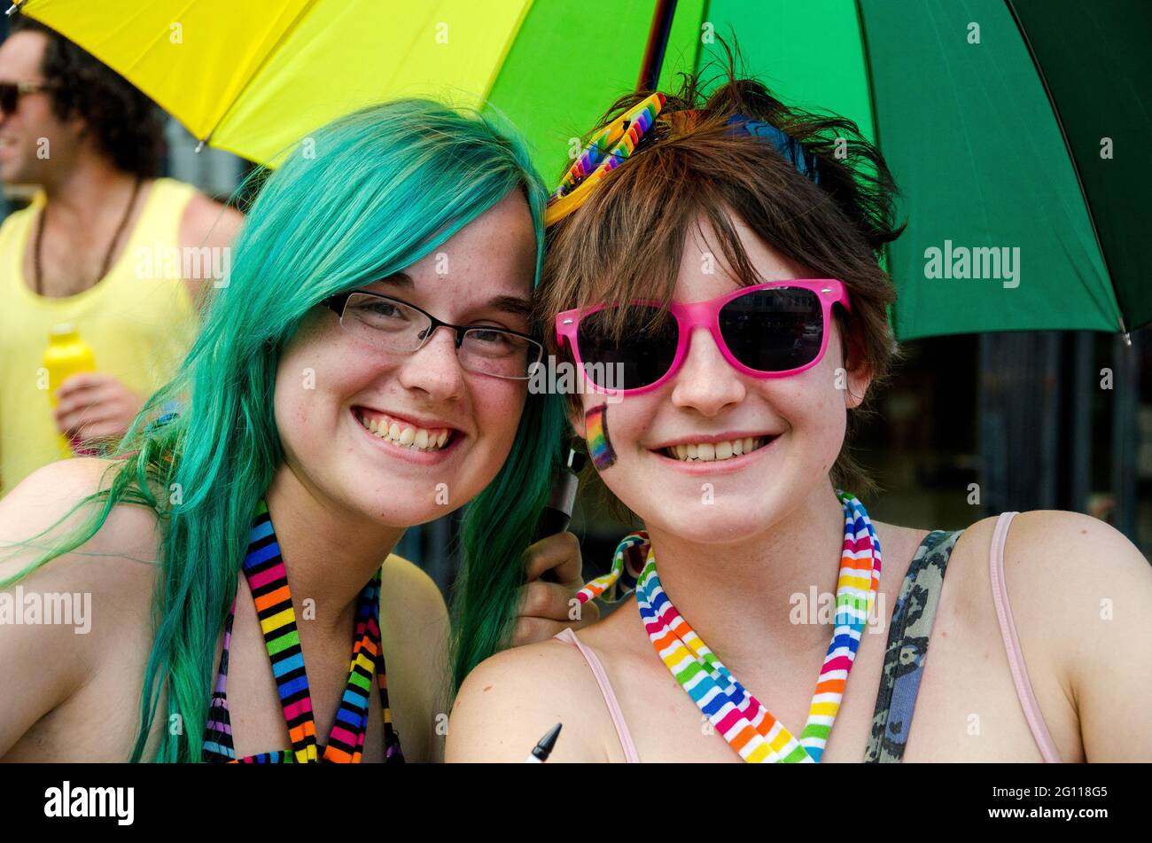 Two smiling women at pride parade Toronto, celebrating in bright, rainbow colored attire Stock Photo