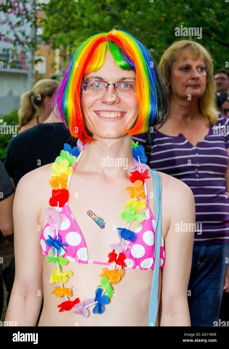 toronto pride parade, girl in a pink polka dot bikini with flower hawaii necklace, rainbow color hair, blue eyes, wearing glasses and nose ring, mediu Stock Photo