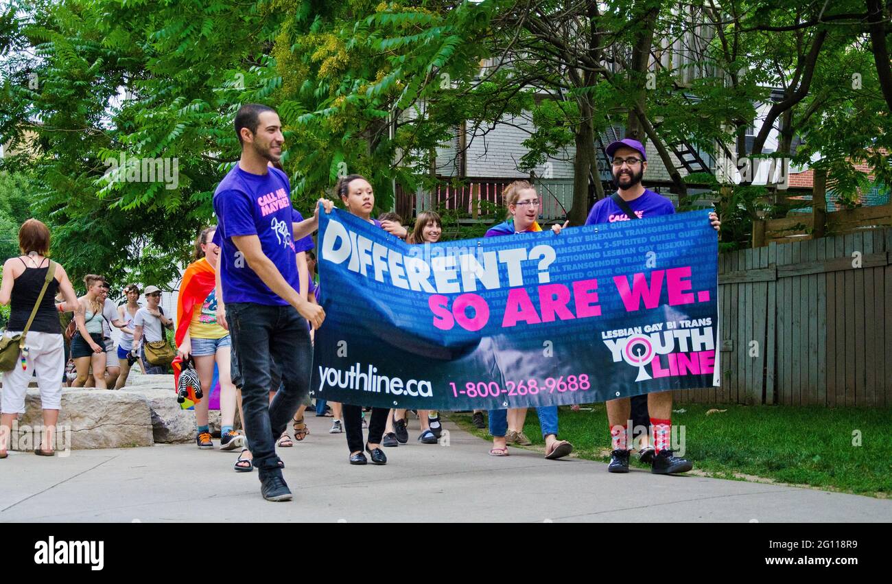 Multicultural group at pride parade Toronto walking down a garden path holding a blue banner Stock Photo
