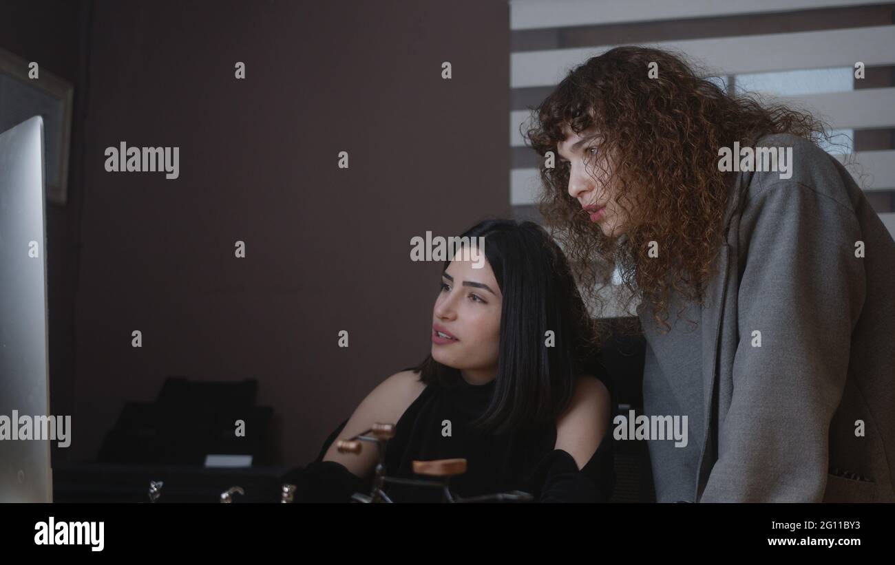 Beautiful business woman listens to professional advisor in her office, they discuss data show on a computer. Stock Photo