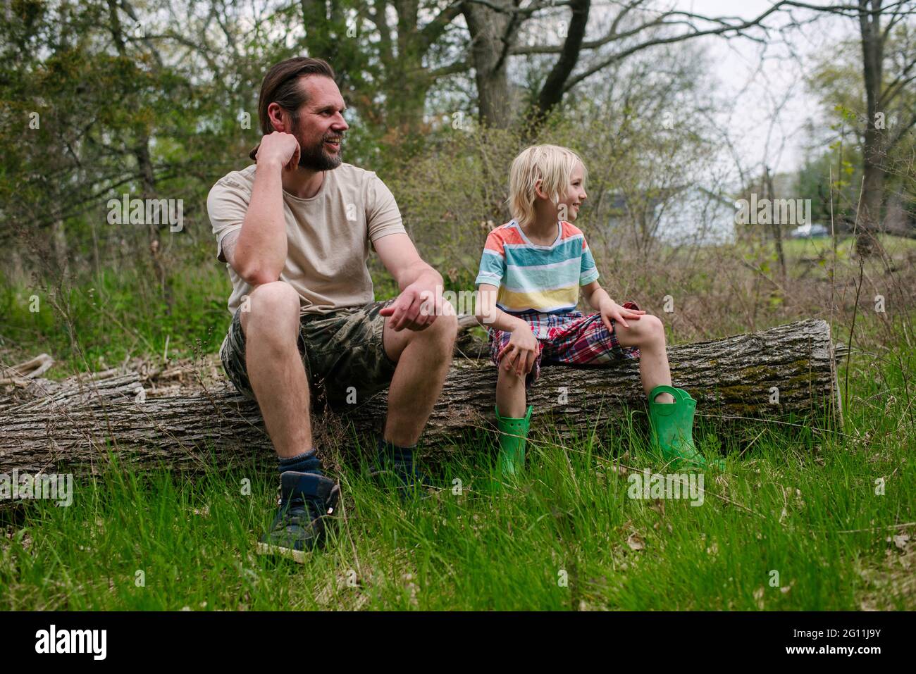 Canada, Ontario, Kingston, Father and son sitting on log in forest Stock Photo