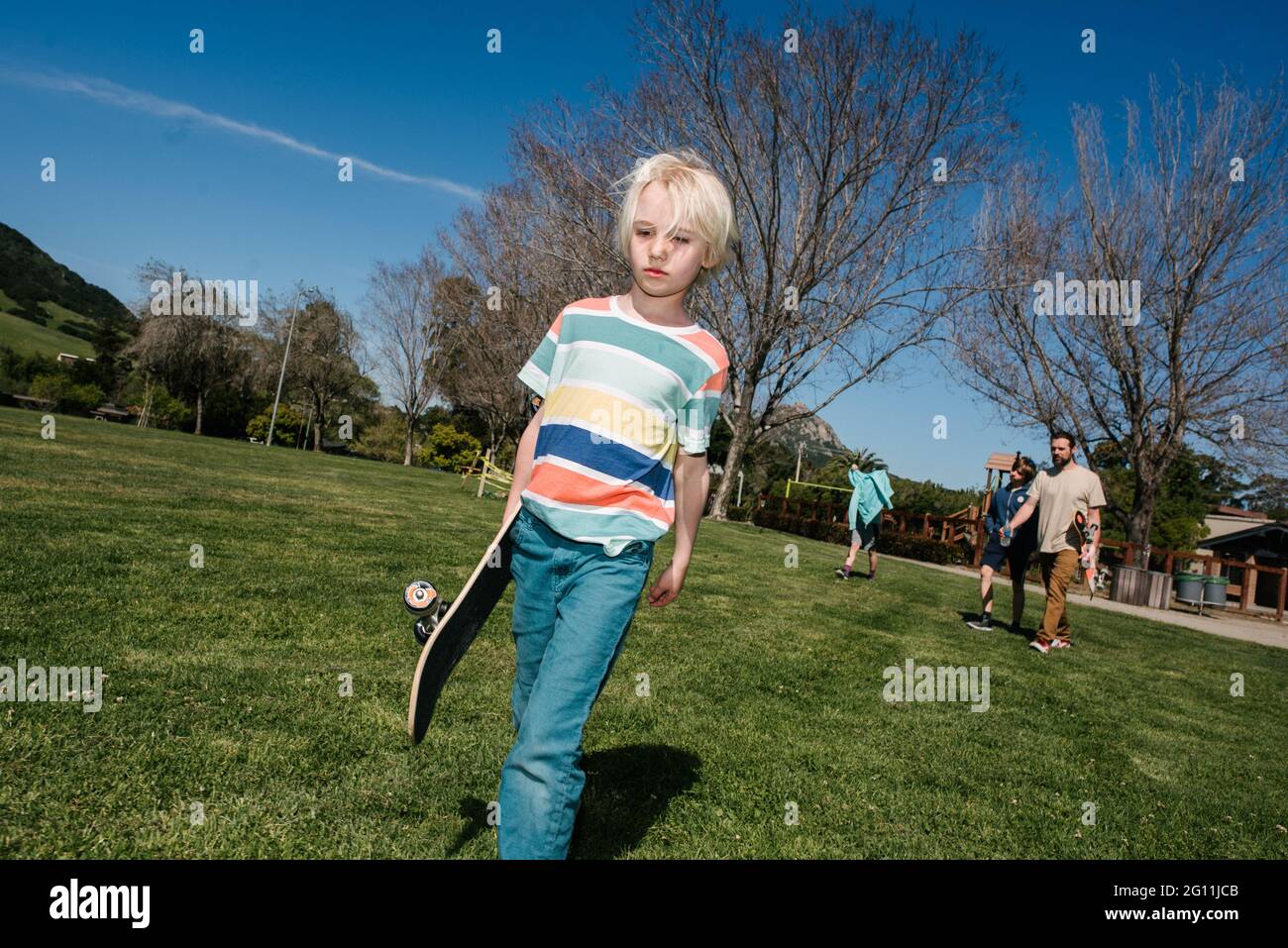 USA, California, Big Sur, Boy with skateboard walking in park Stock Photo