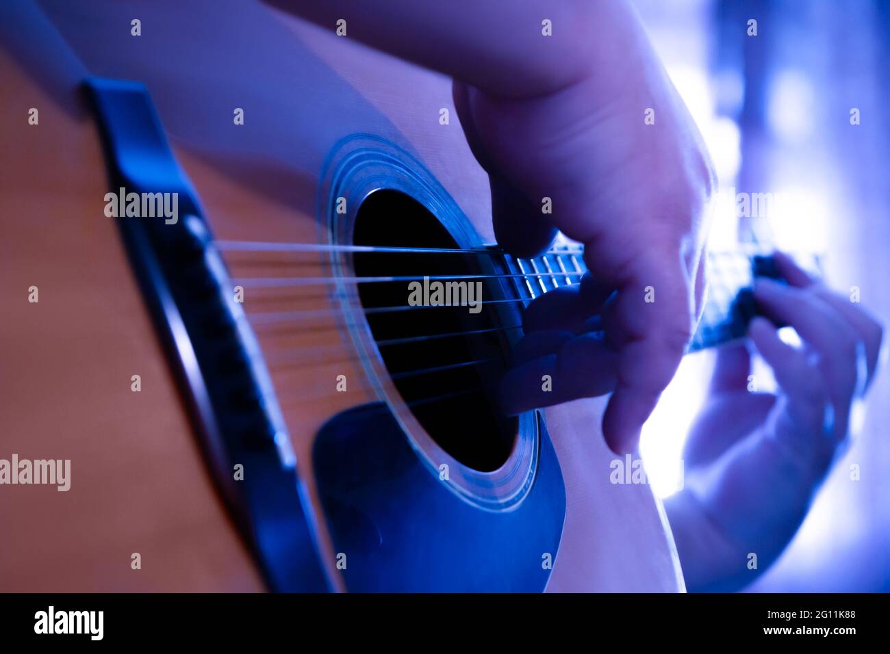 Male hands playing fingers style on a western dreadnought guitar in blue  neon light Stock Photo - Alamy