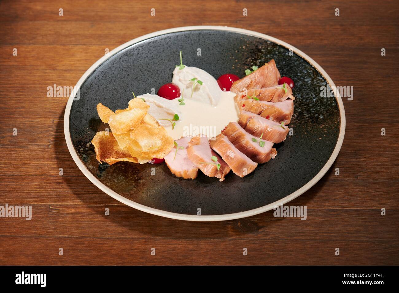 Healthy dinner meal on black plate table. Sliced pork meal Stock Photo