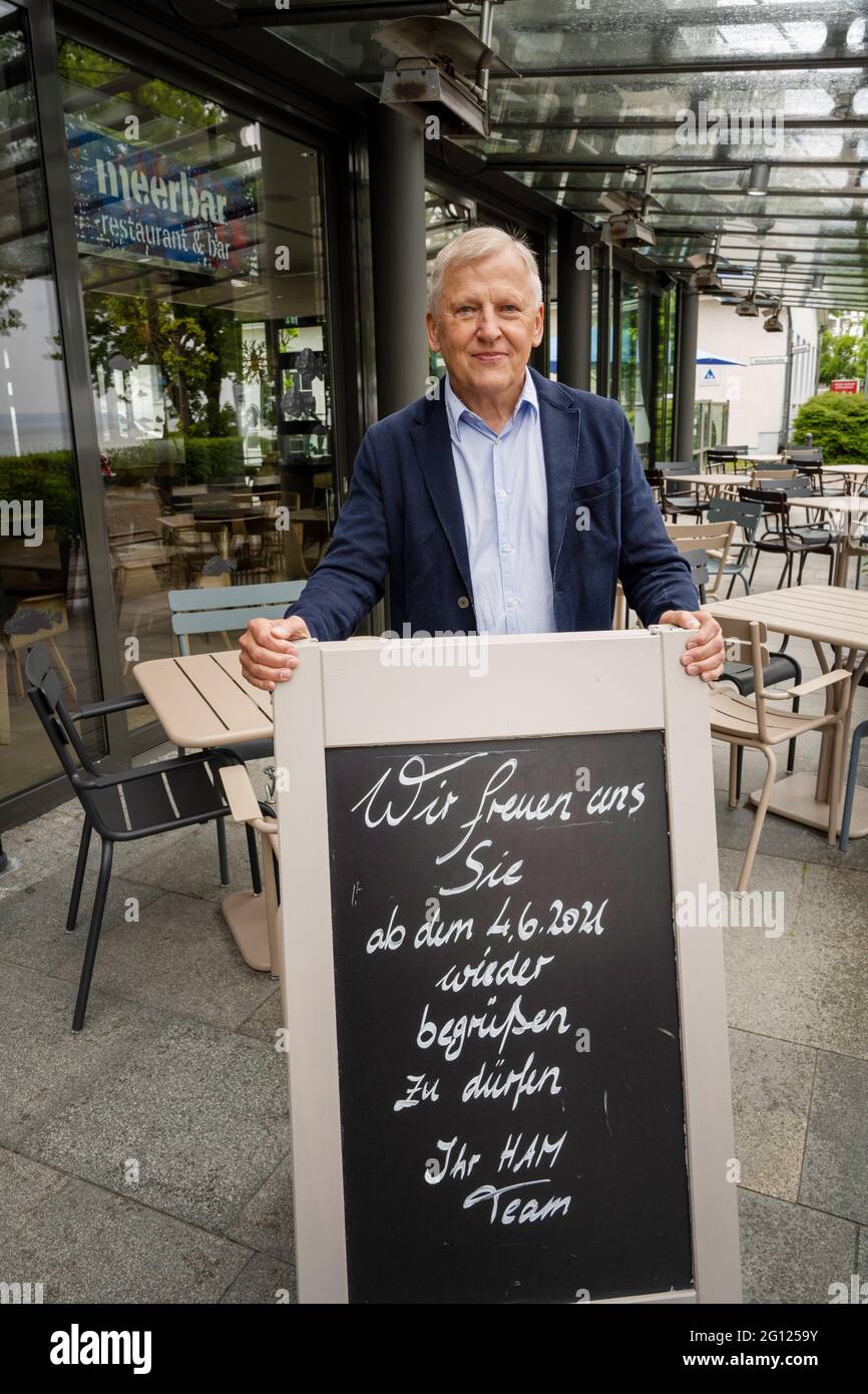 Binz, Germany. 04th June, 2021. Rügen native and hotelier Wolfgang Schewe stands on the terrace of his hotel 'Hotel am Meer & Spa' on the island of Rügen behind a board with the inscription 'We are pleased to welcome you back from 04.06.'. One week after the opening of hotels and other hostels for local holidaymakers, tourists from all over Germany can now come to Mecklenburg-Vorpommern. Credit: Stefan Sauer/dpa/Alamy Live News Stock Photo