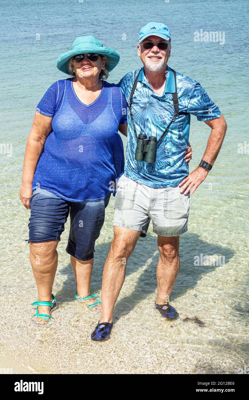 Florida FL Sanibel Island Pine Island Sound Causeway Islands Park beach man woman couple mature wading looking at water surface blue shades matching c Stock Photo