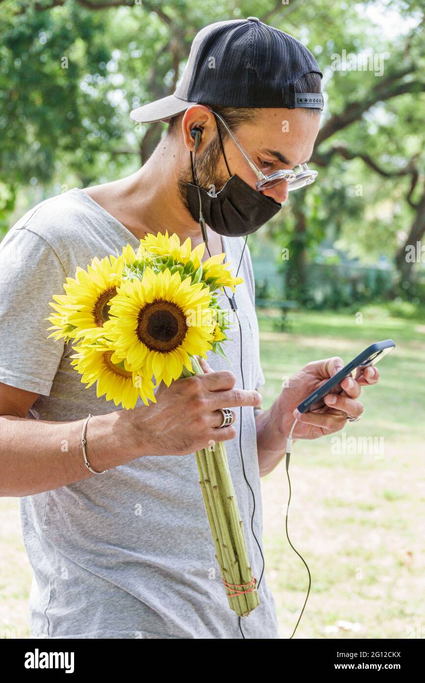 Miami Florida,Legion Park Farmers Market day,man men male adult adults,holding sunflowers smartphone smartphones mobile cell smart phone phones,textin Stock Photo