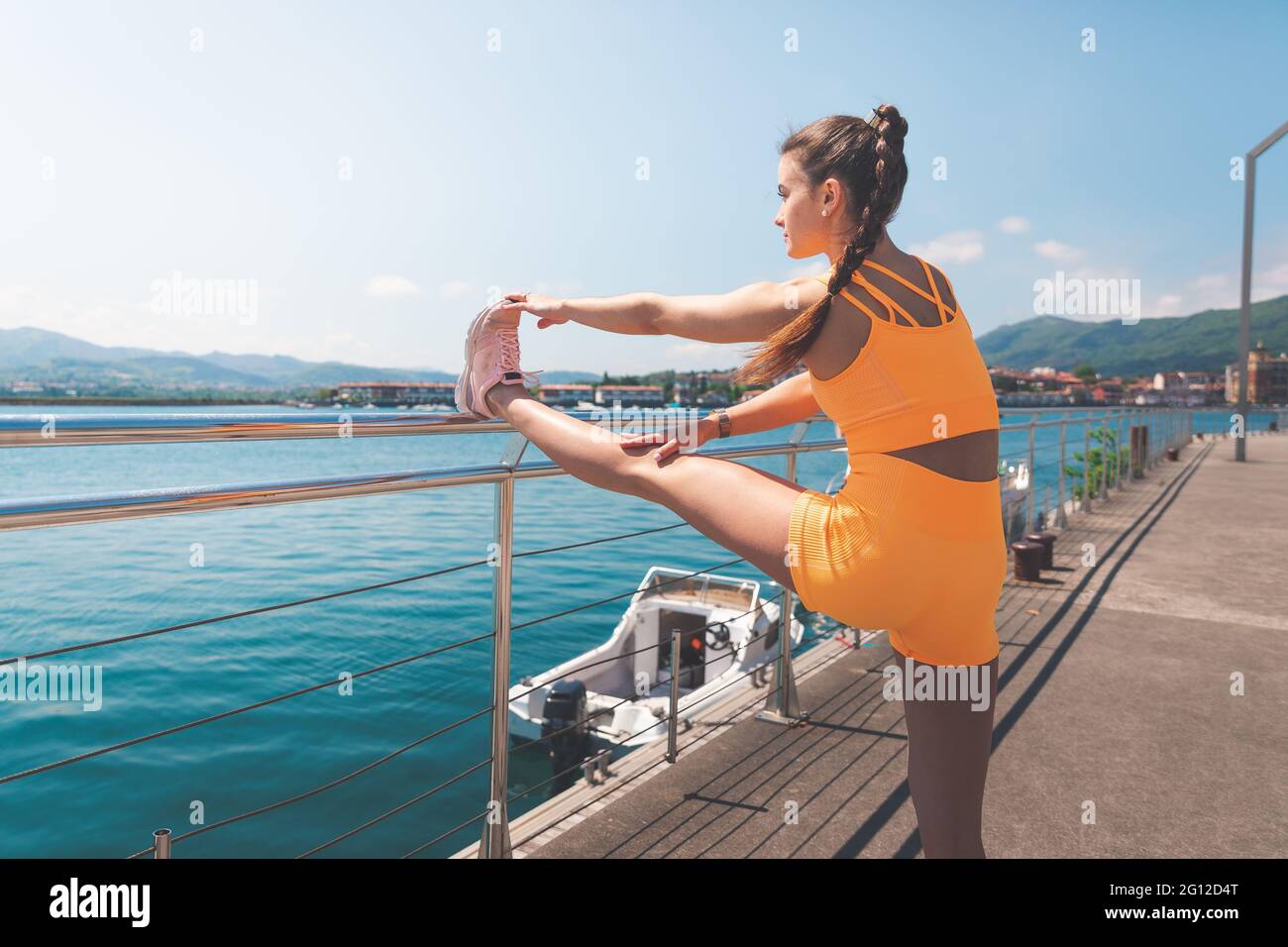 Stretch Basque Young woman stretching with an orange wearing at the marina of Hendaia ...