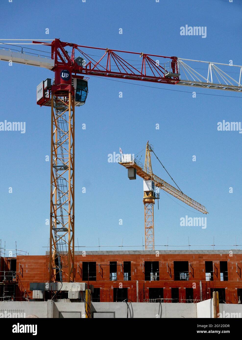 A construction worker in the distance checks new work done on a building housing. Stock Photo