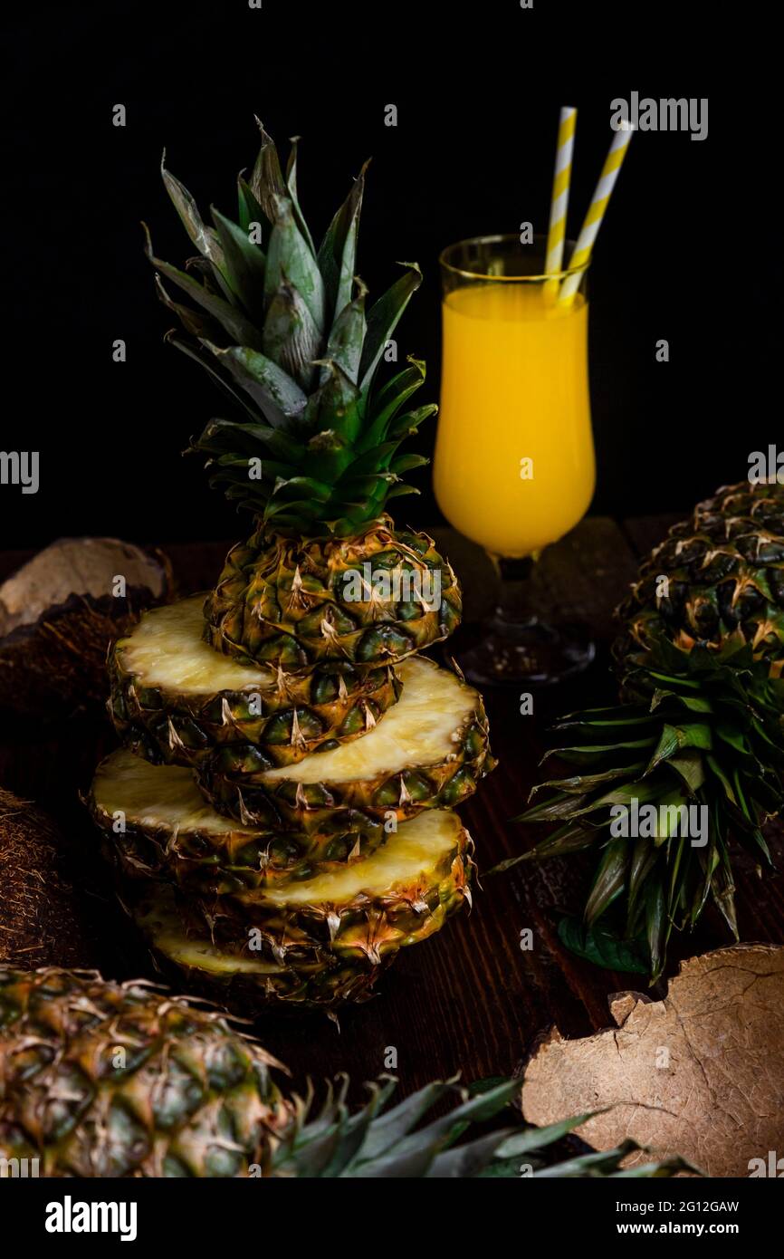 Sliced Pineapple fruit with juice in a glass in background. Stock Photo
