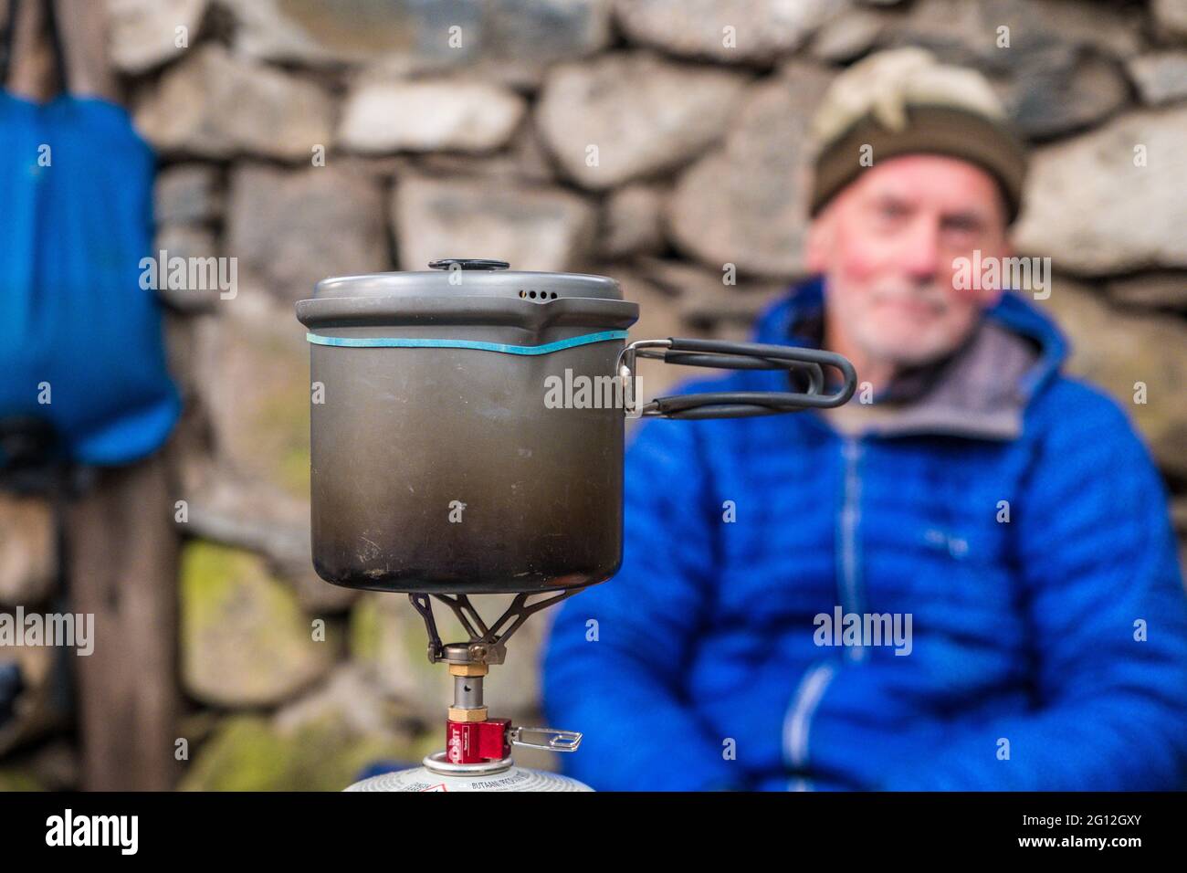 Male backpacker cooking on a backpacking gas stove in a Scottish bothy Stock Photo