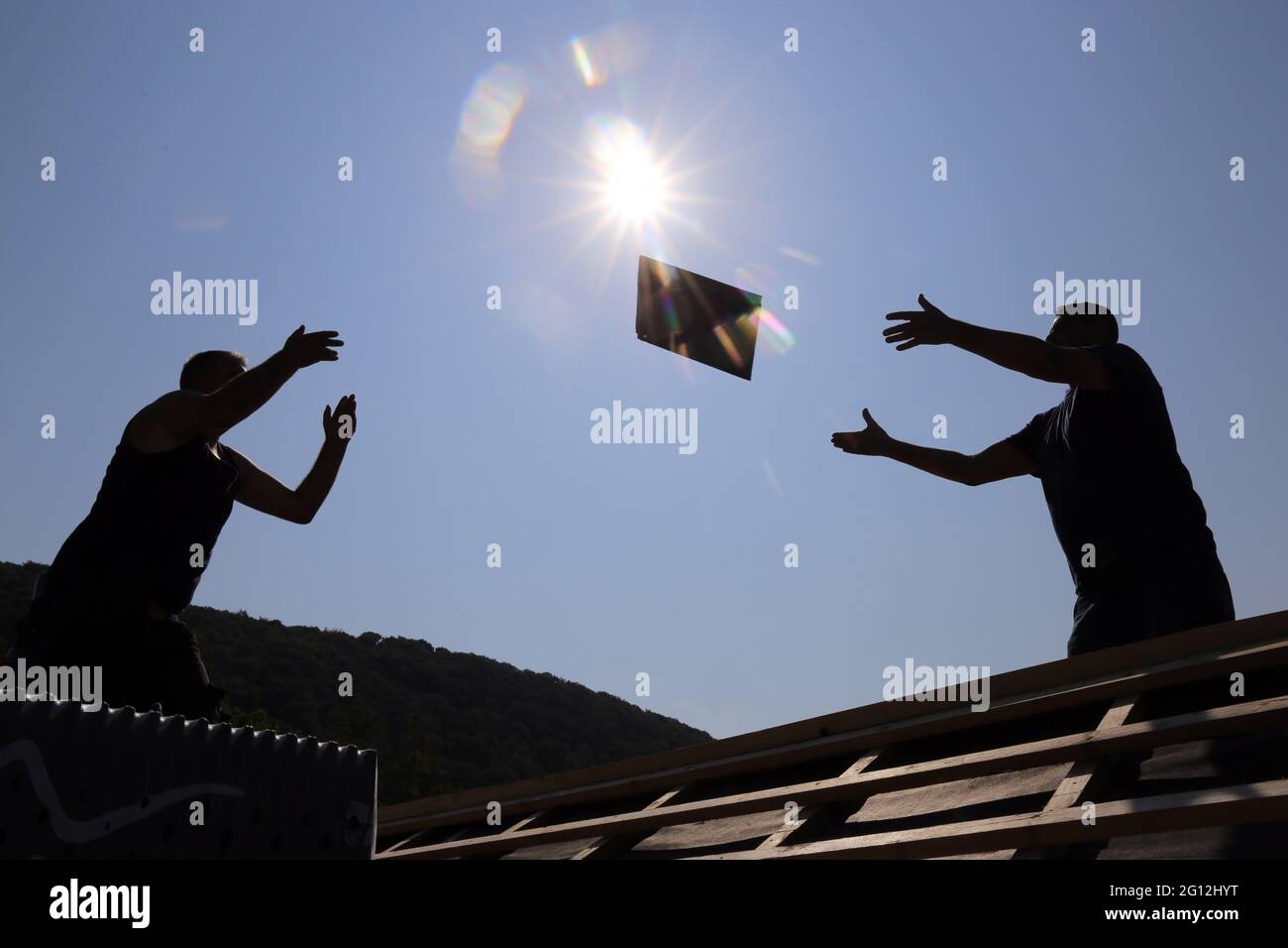 Silhouettes of roofers in the backlight. Stock Photo