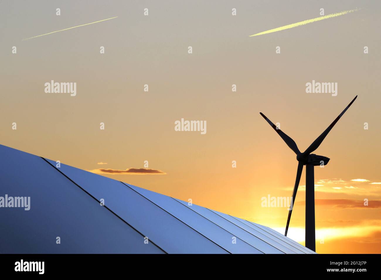 Symbol image: Solar park with wind turbines in the background. Stock Photo