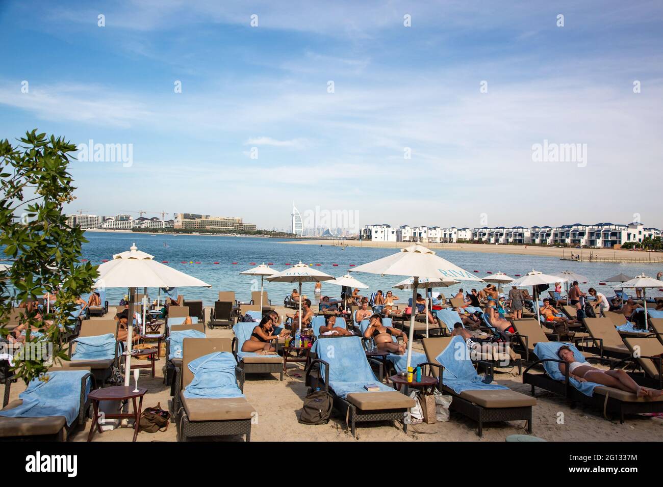 Tourists sunbathing on Palm Jumeirah with Burj Al Arab in the background.  Dubai, 2.Dec. 2018 Stock Photo