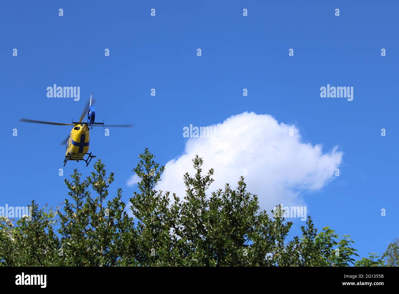 Air ambulance in a bright blue sky. G-NWEM Eurocopter EC-135 of the North West Air Ambulance woth copy space Stock Photo